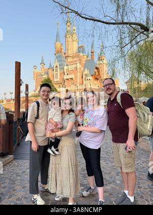 Shanghai. März 2025. Brecken Neumanns Familie und Rong Rongs Familie posieren für ein Gruppenfoto im Shanghai Disneyland im ostchinesischen Shanghai am 25. März 2025. ZU DEN THEMEN „Across China: From Netizens to Travel Pals: American, Chinese Family Meet in Shanghai“ Credit: Xinhua/Alamy Live News Stockfoto