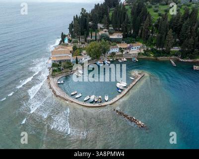 korfu, korfu, Griechenland. 15. März 2025: Blick aus der Vogelperspektive auf einen malerischen Hafen in Griechenland mit Booten, die entlang einer gekrümmten Pier vertäut sind. Stockfoto