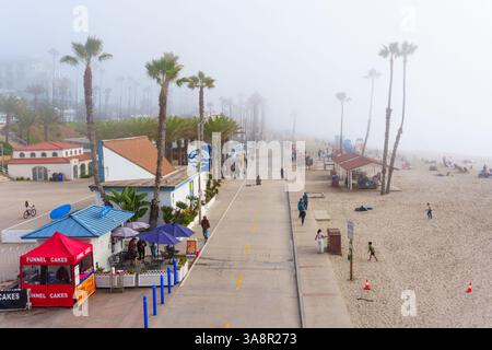 Oceanside, Kalifornien - 3. Januar 2025: Nebeliger Morgen am Oceanside City Beach in Kalifornien, mit einem breiten Fußweg gesäumt von Palmen und Strandgoe Stockfoto