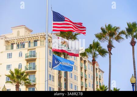 Oceanside, Kalifornien - 3. Januar 2025: Weitwinkelaufnahme amerikanischer und kalifornischer Flaggen, die vor dem Hintergrund des Club Wyndham Oceanside Pier R schwenken Stockfoto
