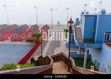Oceanside, Kalifornien - 3. Januar 2025: Blick auf die pulsierenden Roberts Cottages mit Palmen und nebligem Strand in Oceanside, mit einer ruhigen Küste Stockfoto