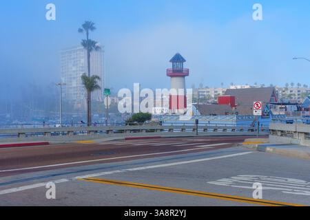 Oceanside, Kalifornien - 3. Januar 2025: Beschauliche nebelige Morgenszene im Oceanside Harbor Village mit einem Leuchtturm, Palmen und dem Hafen Stockfoto