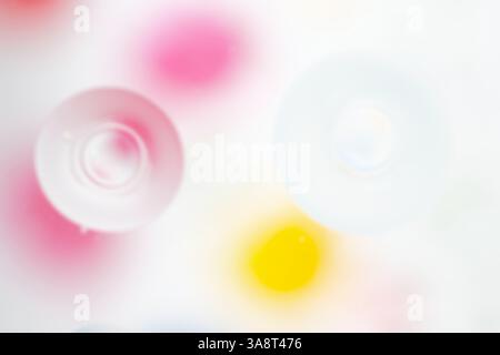 Makrofoto von Ölblasen im Wasser in leuchtenden Gelb-, Rosa- und Weißtönen. Energiegeladene und künstlerische Komposition. Kopierbereich Stockfoto