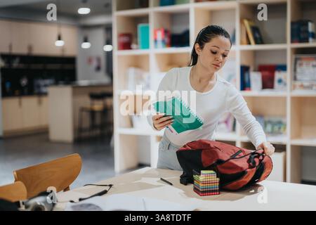 Junge Frau, die Studienmaterialien in einer modernen Bibliothek organisiert Stockfoto