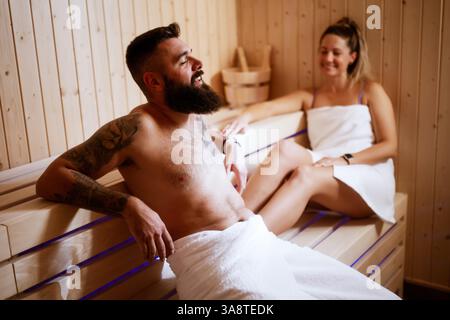 In weiche Handtücher gehüllt, genießt ein Paar eine private Sauna in einem gehobenen Spa. Stockfoto