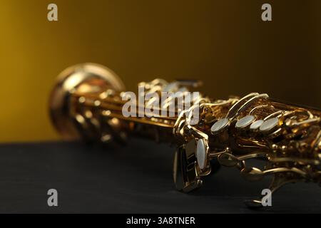 Jazz. Ein schönes Saxophon auf schwarzem Tisch vor farbigem Hintergrund, Nahaufnahme Stockfoto