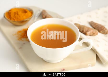 Aromatischer Kurkuma-Tee, Pulver und Rhizome auf weißem Tisch, Nahaufnahme Stockfoto