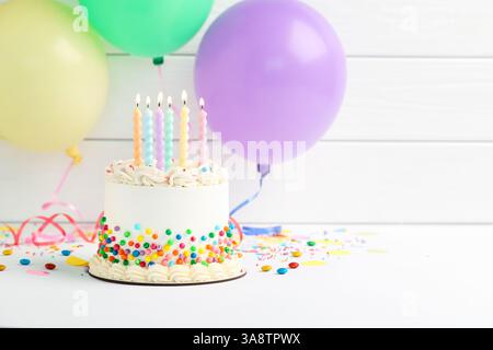 Köstlicher bento-Kuchen mit bunten Streuseln und brennenden Kerzen auf weißem Tisch. Leerzeichen für Text Stockfoto