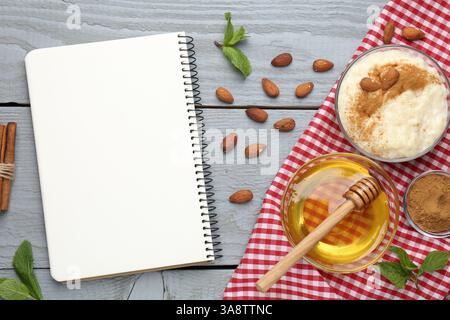 Leeres Rezeptbuch, Dessert und Zutaten auf grauem Holztisch, flache Ladefläche Stockfoto