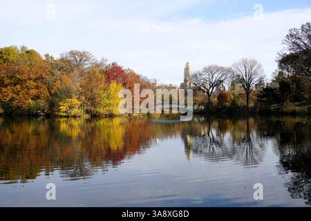 Wunderschönes Panorama der Bow Bridge über den Central Park Lake, New York, während sich an einem sonnigen Herbsttag bunte Blätter von Bäumen im Wasser spiegeln Stockfoto