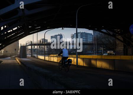 Warschau, Polen. 27. Januar 2025 - Radfahrer reiten unter der Poniatowski-Brücke im frühen Morgenlicht. Stockfoto