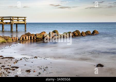 Holzpfeiler und Mole am Ufer der Ostsee in Deutschland am Abend. Foto mit langer Verschlusszeit. Stockfoto