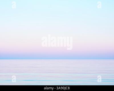 Weicher Himmel in Pastellfarben, der sich in ein ruhiges Meer verwandelt. Minimalistische und traumhafte Atmosphäre Stockfoto