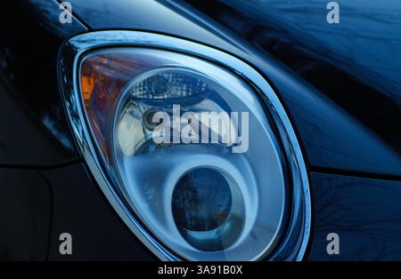 Ein Nahaufnahme-Foto, das das schlanke Design und die komplizierten Details des Scheinwerfers eines schwarzen Alfa Romeo zeigt. Das Bild konzentriert sich auf die präzisen Linien Stockfoto