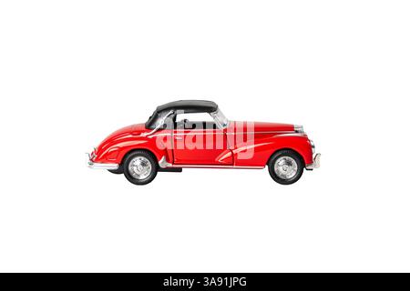 Ein rotes Auto mit schwarzem Dach steht auf weißem Hintergrund. Das Auto ist ein klassisches Modell und hat ein Vintage-Flair. Die rote Farbe des Autos steht o Stockfoto