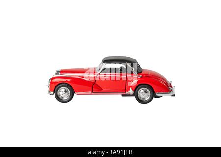 Ein rotes Auto mit schwarzem Dach steht auf weißem Hintergrund. Das Auto ist ein klassisches Modell und hat ein Vintage-Flair. Die rote Farbe des Autos steht o Stockfoto