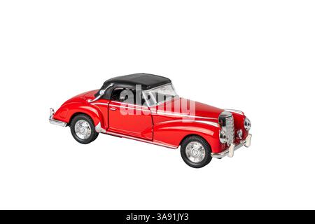 Ein rotes Auto mit schwarzem Dach steht auf weißem Hintergrund. Das Auto ist ein klassisches Modell und hat ein Vintage-Flair. Die rote Farbe des Autos steht o Stockfoto