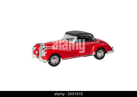 Ein rotes Auto mit schwarzem Dach steht auf weißem Hintergrund. Das Auto ist ein klassisches Modell und hat ein Vintage-Flair. Die rote Farbe des Autos steht o Stockfoto