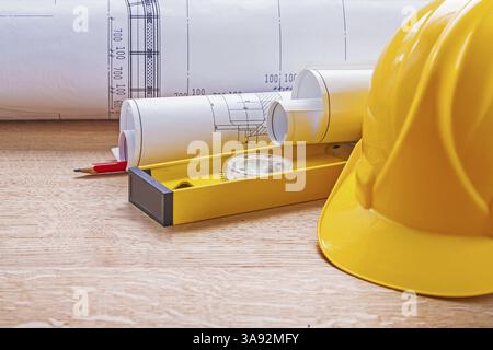 Blick auf gelbe Helmhöhe Blaupausen Bleistift Holzbrett-Konstruktionskonzept Stockfoto