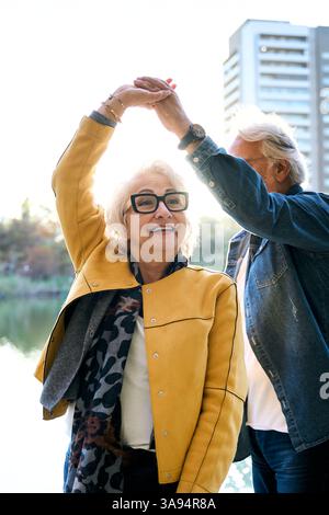 Glückliches Seniorenpaar, das am See in der Stadt tanzt Stockfoto
