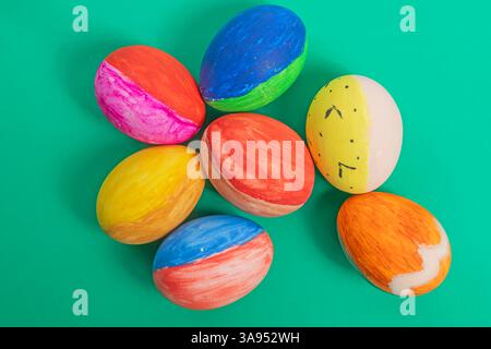 Lebendig dekorierte Ostereier in verschiedenen Farben und verspieltem Design auf einer hellgrünen Oberfläche, symbolisieren Feiertagsaufregung, Kreativität und festliches Stockfoto