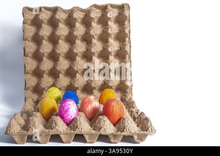 Sieben hell bemalte Ostereier in einem Karton auf weißem Hintergrund, Feiertagsfeier Stockfoto
