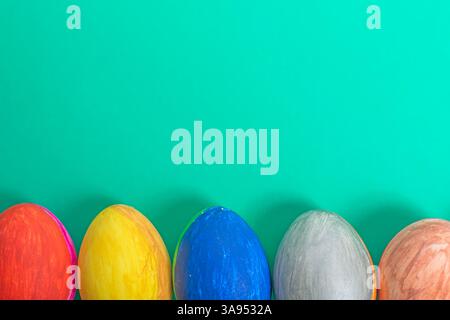 Eine Vielzahl von bunt bemalten Ostereiern, die Freude und Feier symbolisieren, sind auf einem leuchtend grünen Hintergrund platziert. Stockfoto