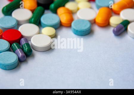 Draufsicht auf farbenfrohe Pillen und Kapseln, die auf einer hellen Oberfläche mit anpassbarem Platz für Text verstreut sind Stockfoto