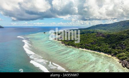 Ein abgelegener Strand mit kristallklarem Wasser, umgeben von Granitfelsen und dichter Vegetation. Seychellen, La Digue. Stockfoto