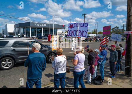 Demonstranten halten während eines Protestes gegen den CEO Anti-Elon Musk und verteidigen Demokratiezeichen gegenüber dem Tesla-Händler am Arden Way. Stockfoto