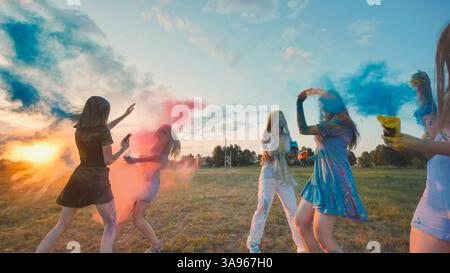 Junge Frauen, die das holi-Festival genießen, beim Sonnenuntergang farbiges Pulver in die Luft werfen, Freundschaft und Einheit begrüßen Stockfoto