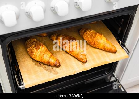 Geröstete Croissants liegen auf einem Backblech im Ofen. Backblech mit Croissants. Croissant mit knuspriger Kruste Stockfoto