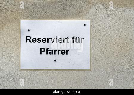 Schild vor einer Kirche mit der deutschen Inschrift reserviert für Pfarrer. Übersetzung: Für Pastor reserviert Stockfoto