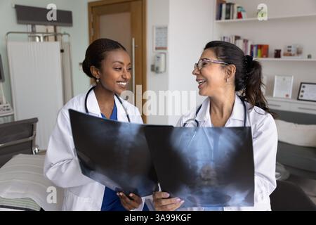 Positive junge und leitende Ärzte mit Röntgenaufnahmen von Knochen Stockfoto