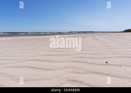 Sandstrand mit welliger Sandstruktur und Meer im Hintergrund. Stockfoto
