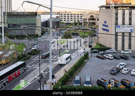 New Orleans, Louisiana USA 28. Februar 2025 Polizei Motorrad Harley Davidson hielt an einer Kreuzung, Leute laufen, Lichtmast, P-Schild, Limo, VIP Stockfoto