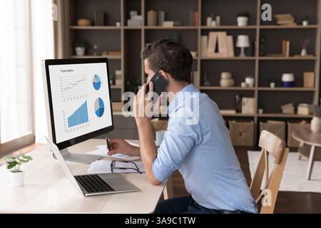 Geschäftsmann, der aus der Ferne arbeitet, spricht am Telefon und sieht auf dem Computerbildschirm aus Stockfoto