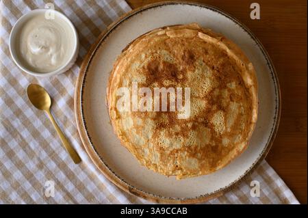 Pfannkuchen mit Honig, Sauerrahm und frischen Erdbeeren in einer warmen, einladenden Umgebung. Stockfoto