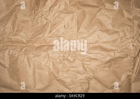Strukturiertes braunes Kraftpapier bedeckt die Oberfläche und zeigt Falten und Falten. Dieses vielseitige Material eignet sich perfekt für verschiedene künstlerische Aktivitäten oder Verpackungsanforderungen. Stockfoto