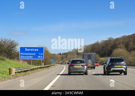 Gloucestershire, England, Vereinigtes Königreich - 29. März 2025: Verkehr auf der Autobahn M5, vorbei an einem Informationsschild, das den Fahrern die Entfernungen bis zur Autobahnverbindung anzeigt Stockfoto