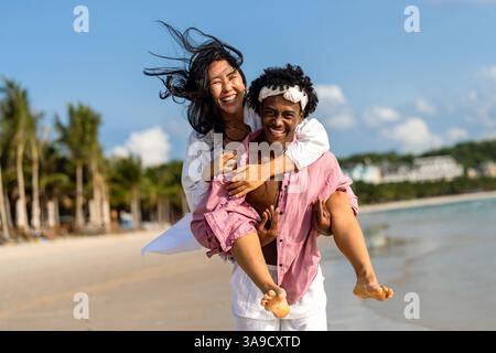 Interrassisches Paar, das einen romantischen Strandurlaub genießt und Liebe, Lachen und Zweisamkeit genießt Stockfoto
