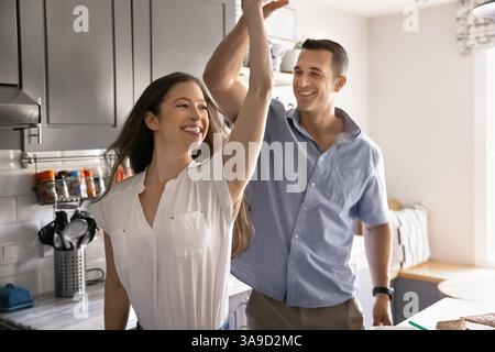 Glückliches junges Paar, das zusammen in der modernen Küche tanzt Stockfoto