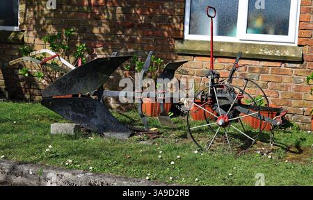 Wie bei der Pensionierung alter Landwirte können sie an die Arbeit erinnern, in diesem Fall handelt es sich um einen ehemaligen Pferdepflug, der heute ein Gartenschmuck ist Stockfoto