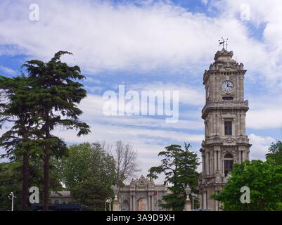 Eingang zum Dolmabahce-Palast mit Uhrenturm unter blauem Himmel mit Wolken. Istanbul Stockfoto