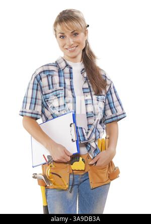 Schöne junge Arbeiterin mit Bauwerkzeugen, die Clipboard halten, lächelnd und auf die Kamera isoliert auf weißem Hintergrund schauen Stockfoto
