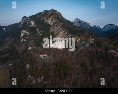 Aus der Vogelperspektive auf Schloss Neuschwanstein mit bewaldeten Bergen Stockfoto