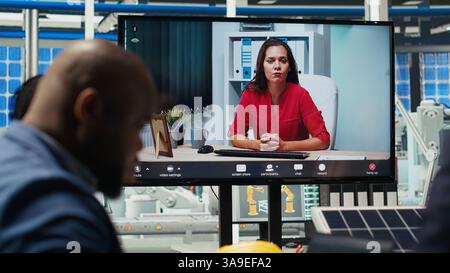 Manager im Büro, die Berichte über Solartechnologie während Internet-Videoaufnahmen überprüfen. Aktionäre bei Ferngesprächen über Investitionsmöglichkeiten in die Erzeugung grüner Energie, Kamera B Stockfoto