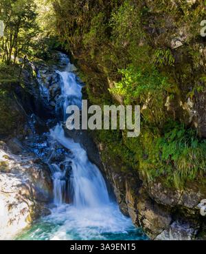 Christie Falls, ein Wasserfall, der sich durch den dichten Regenwald in der Nähe des Highway 94 zum Milford Sound in South Island, Neuseeland, schlängelt Stockfoto