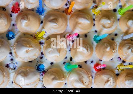 Wunderschöner Geburtstagskuchen mit weißer Schlagsahne, Baisons und Preiselbeeren, dekoriert mit bunten Kerzen. Happy Birthday-Konzept. Muster für Stockfoto