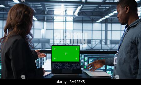 Systemadministratoren von Rechenzentren, die einen Modell-Laptop verwenden, um die Gerätediagnose zu überprüfen. Teamwork-IT-Spezialisten passen die Konfiguration der Serverfarm mit Chroma Key Notebook an Stockfoto